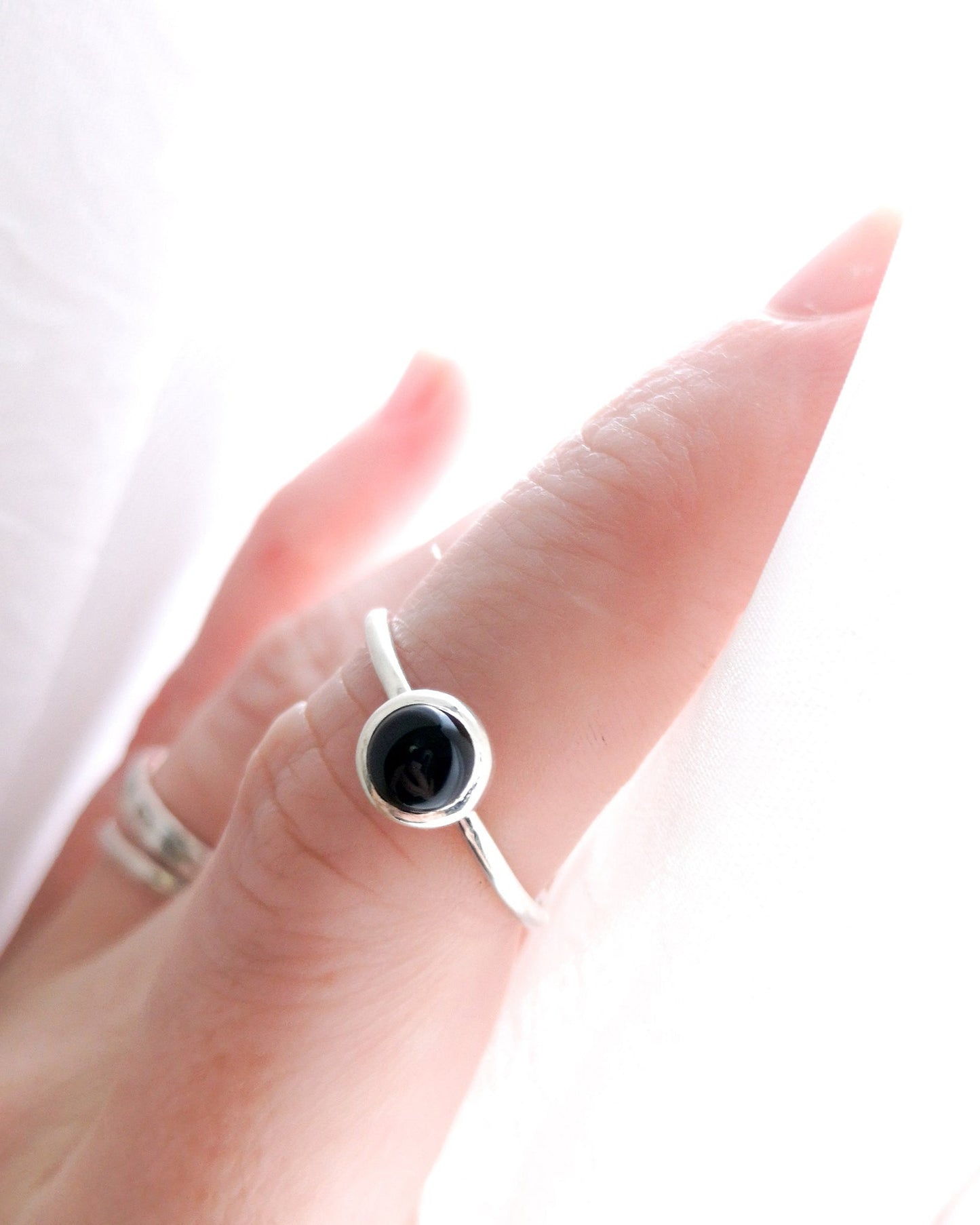Anillo Mirar de la colección Esencial, de plata con una piedra negra redonda en el centro, llevado en el dedo índice de la mano izquierda.