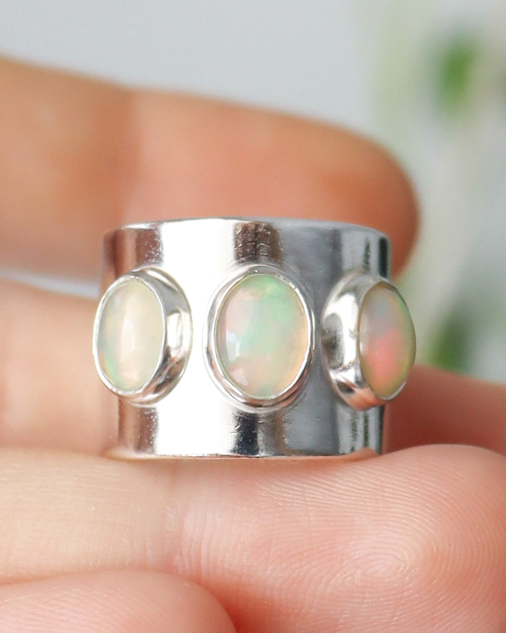 Primer plano del anillo ancho con 3 ópalos etiopes, en una mano.