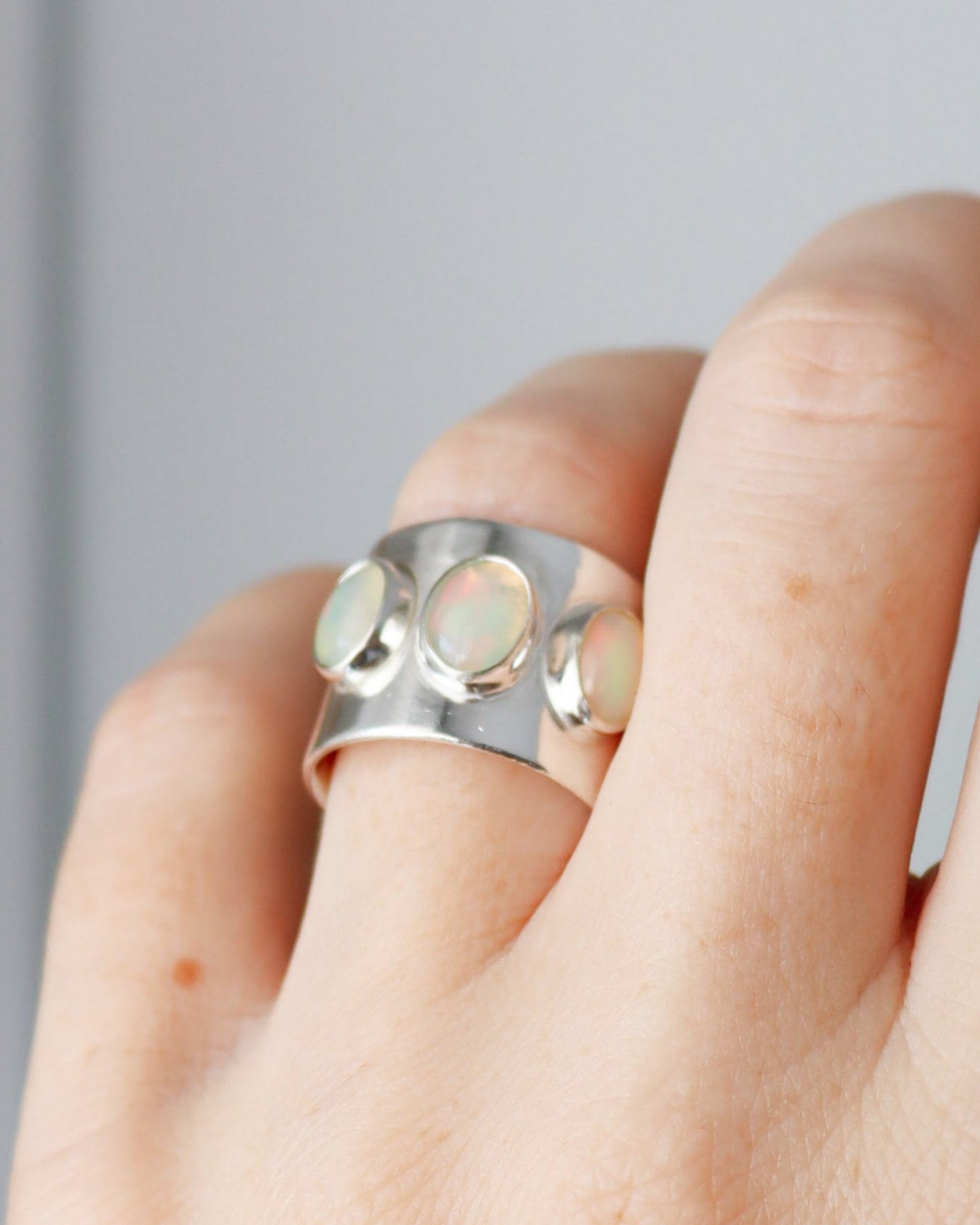 Anillo ancho con 3 opalos etiopes de plata de ley, en dedo anular de mano izquierda.