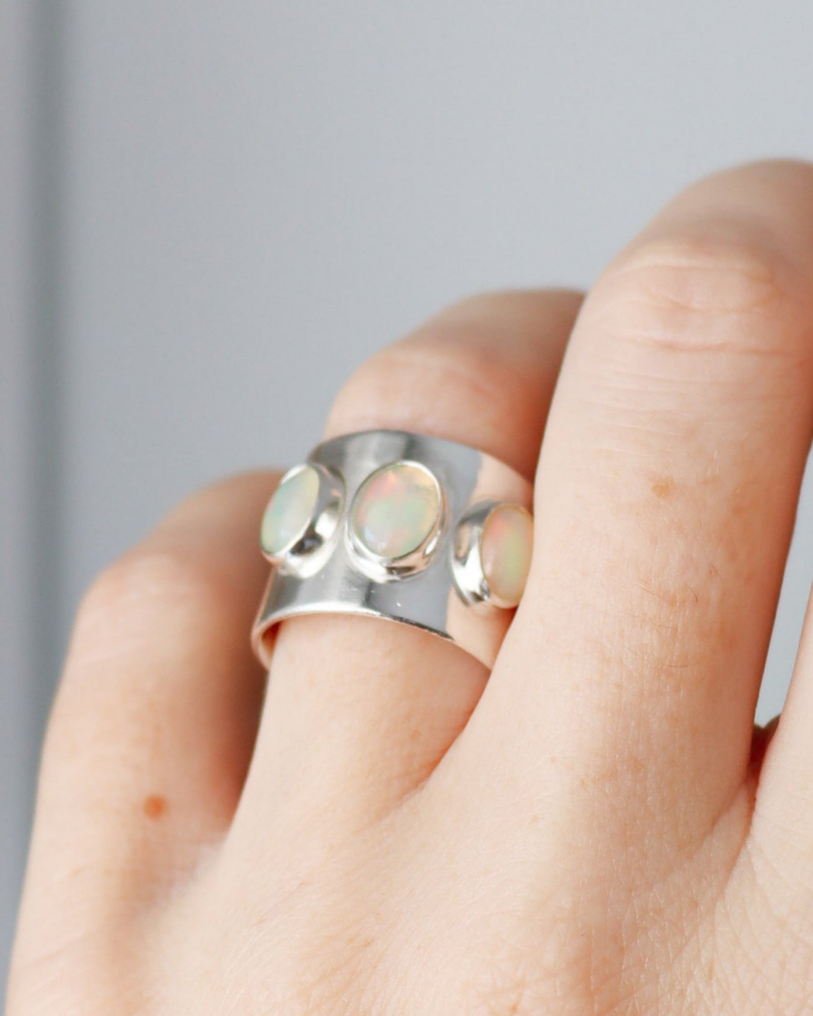 Anillo ancho con 3 opalos etiopes de plata de ley, en dedo anular de mano izquierda.