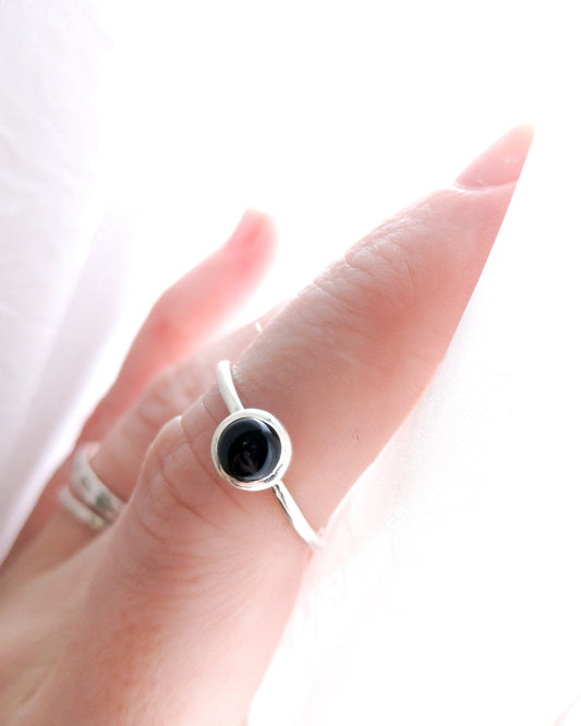 Anillo Mirar de la colección Esencial, de plata con una piedra negra redonda en el centro, llevado en el dedo índice de la mano izquierda.