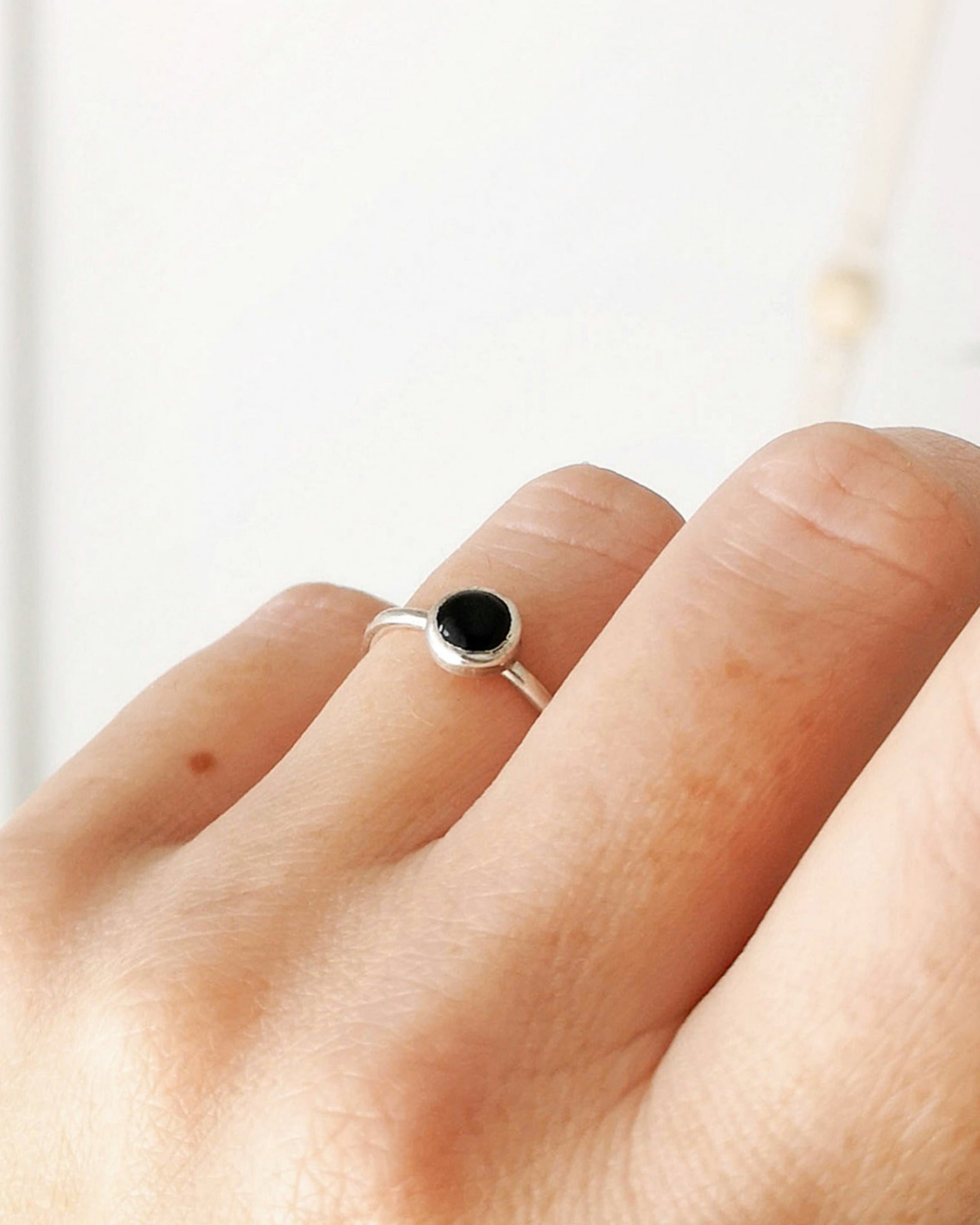 Anillo Mirar de la colección Esencial, de plata con una piedra negra redonda en el centro, llevado en el dedo anular de la mano izquierda.