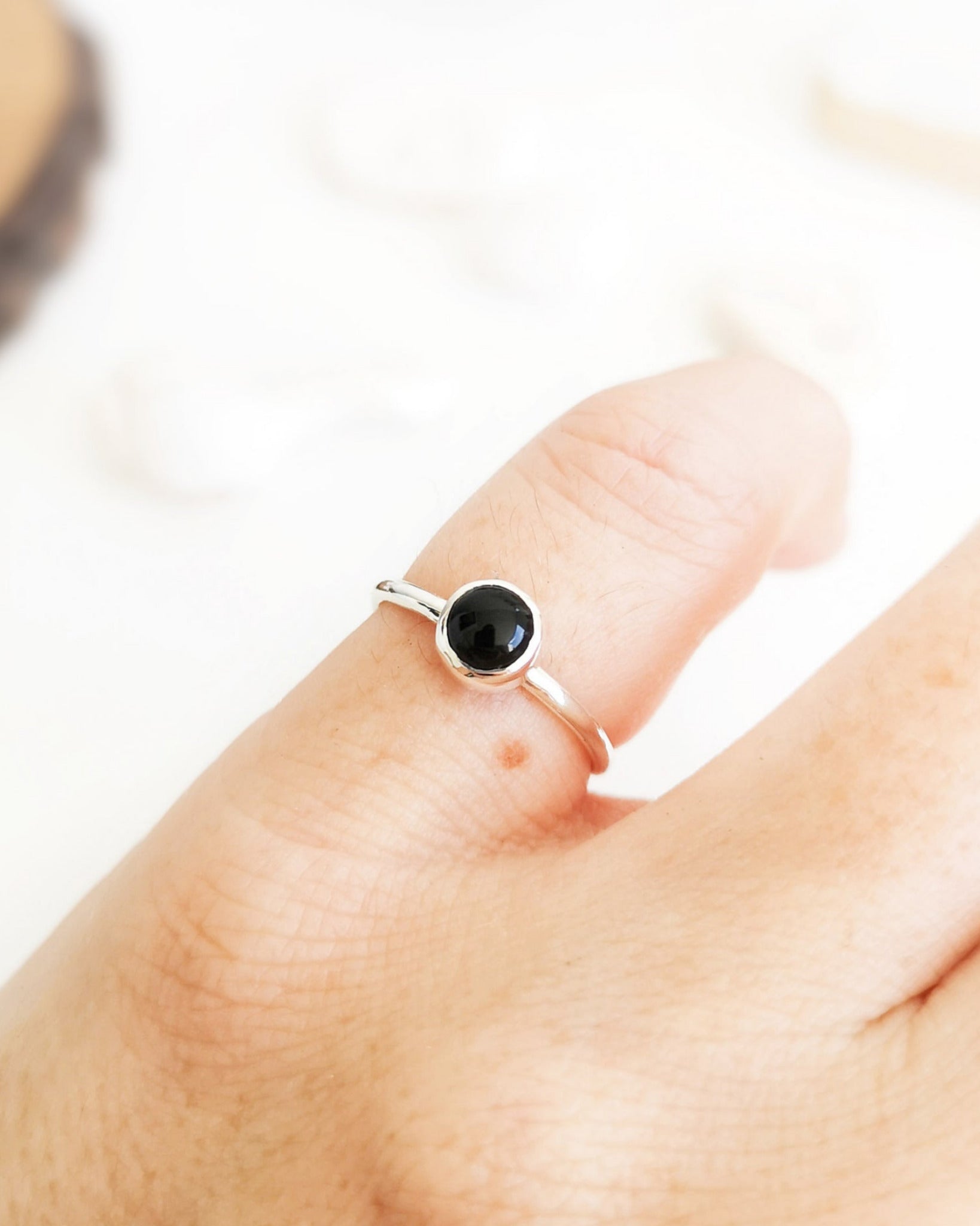 Anillo Mirar de la colección Esencial, de plata con una piedra negra redonda en el centro, llevado en el dedo meñique de la mano izquierda.