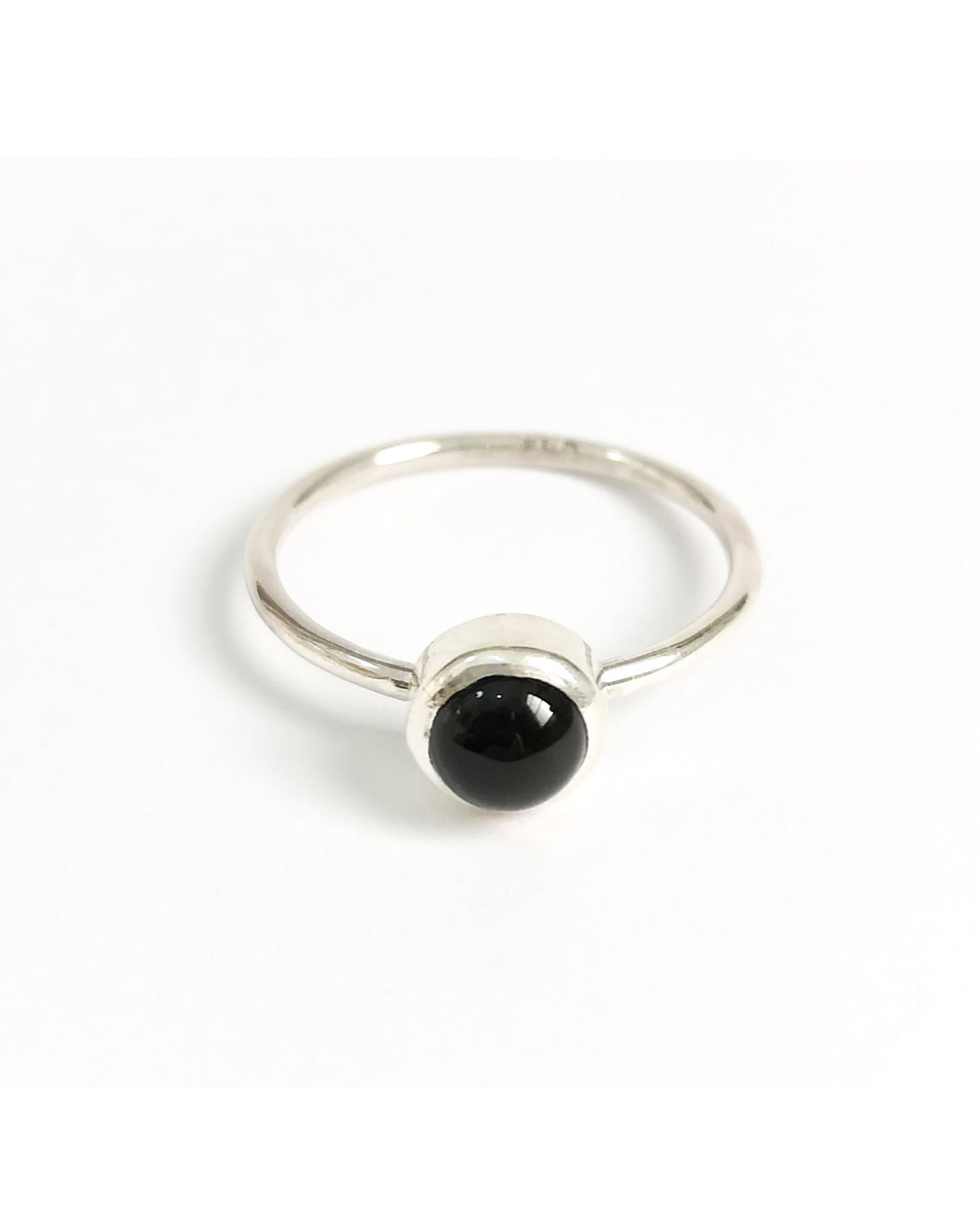 Anillo Ser de la colección Esencial, de plata con una piedra negra redonda central, sobre un fondo blanco.