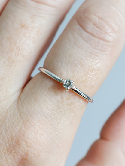 Anillo solitario de plata de ley (plata 925) con topacio blanco talla brillante. Vista en primer plano del anillo puesto en el dedo destacando la brillantez de la piedra redonda y el engaste de tres garras. Diseño fino, elegante y clásico de joyería fina.