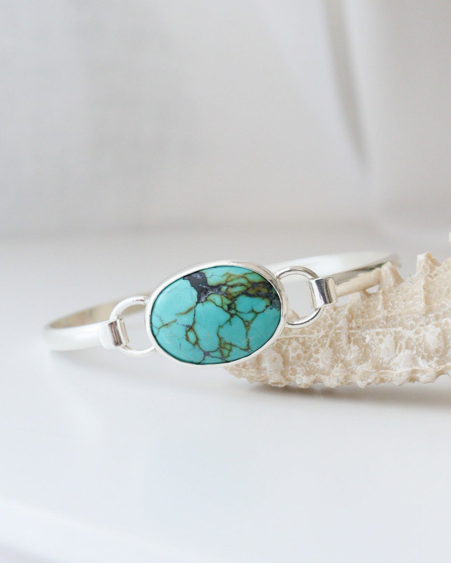 Primer plano de pulsera EUNOIA con turquesa tibetana, apoyada sobre un adorno con forma de coral.