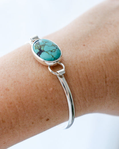 Pulsera EUNOIA con turquesa tibetana de forma ovalada y estructura de plata de ley puesta en la muñeca de una mujer.