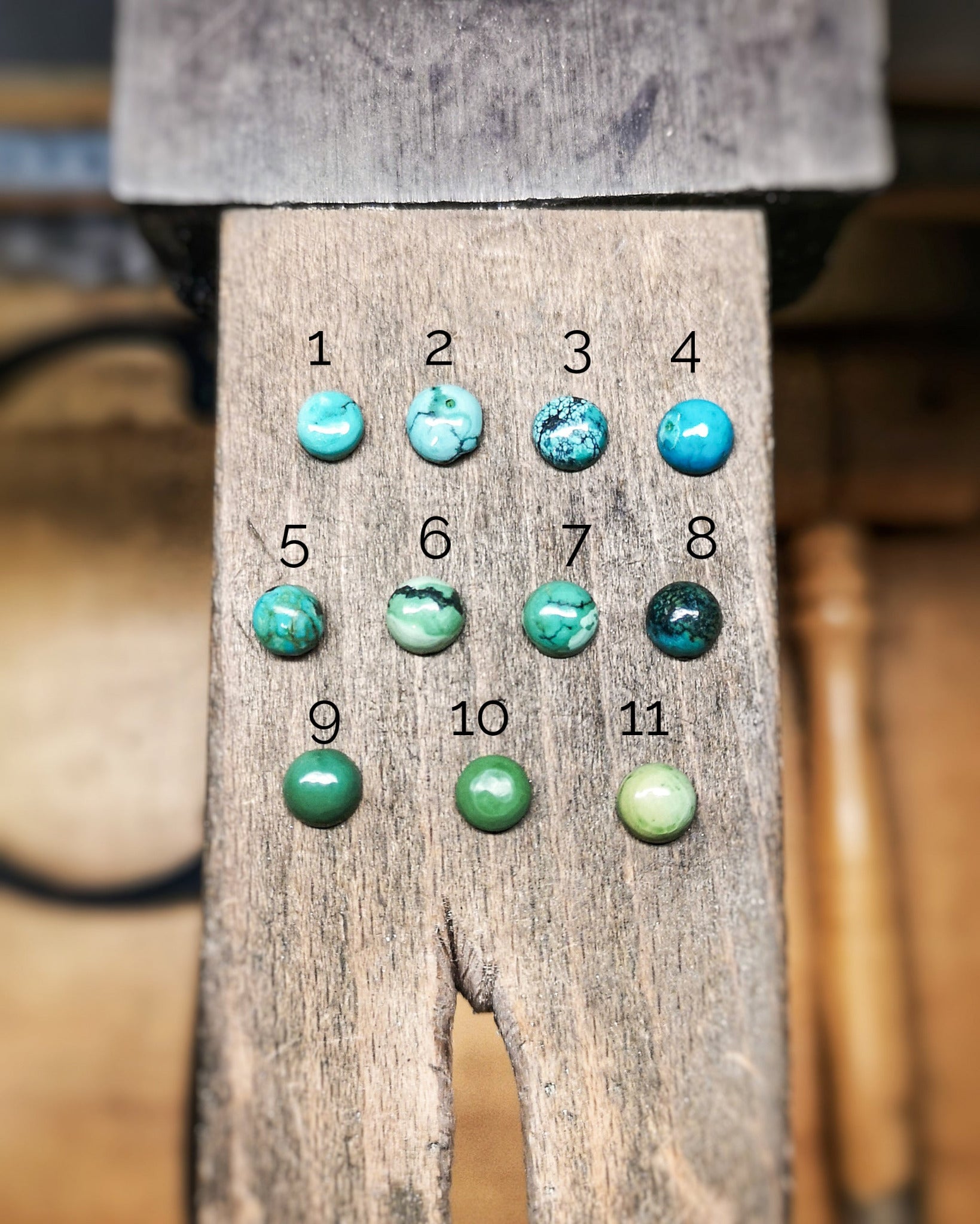 La imagen muestra una pieza de madera rústica con 11 cabujones redondos de turquesa numerados del 1 al 11. Las piedras varían en tonos de azul y verde, algunas con vetas o matrices más pronunciadas.